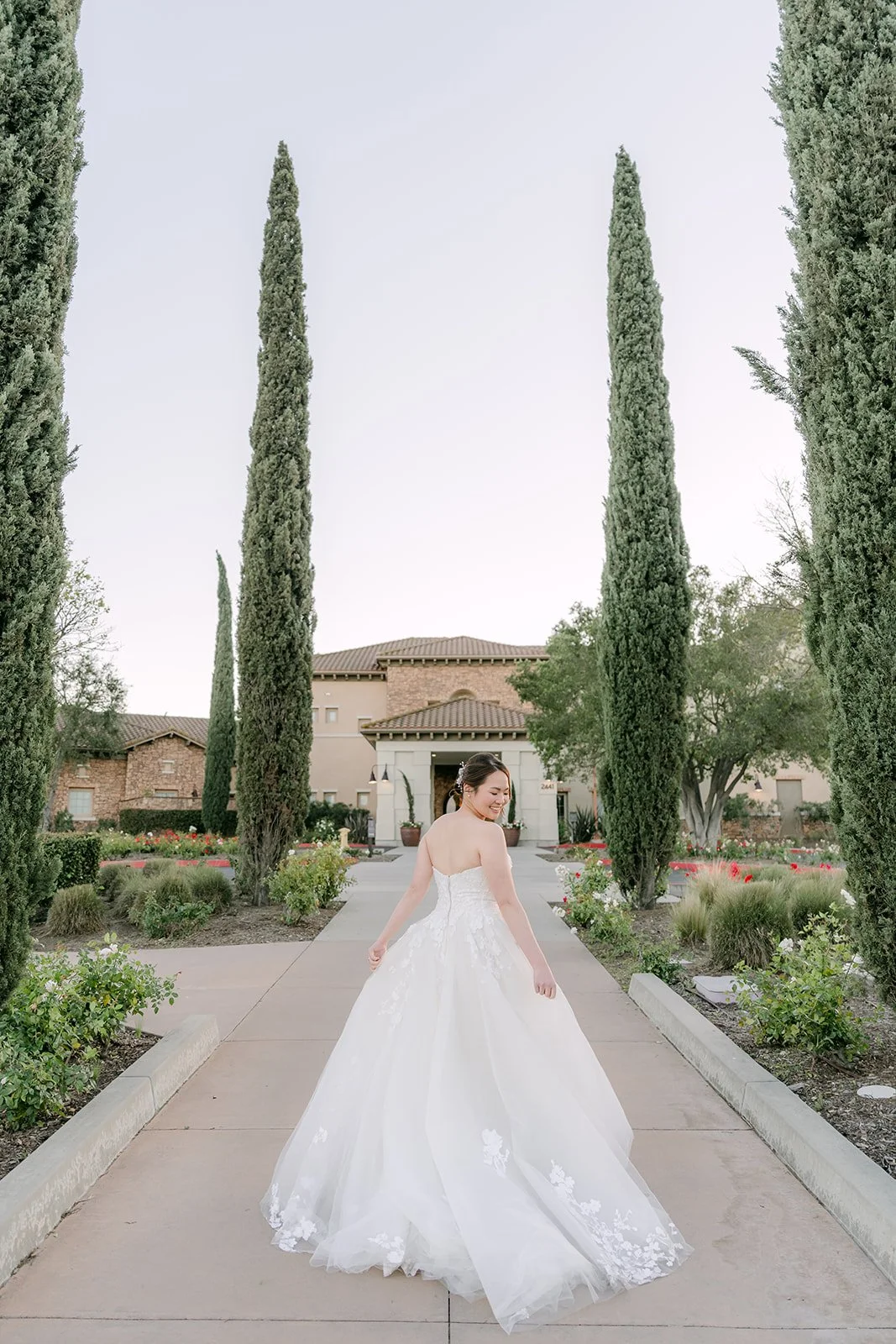Bride walking down the cypress-lined path toward the estate