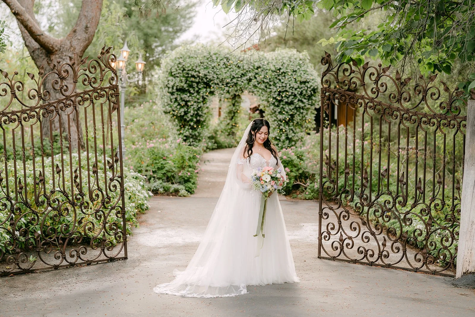Bride framed by the open wrought iron gates at Ethereal Gardens