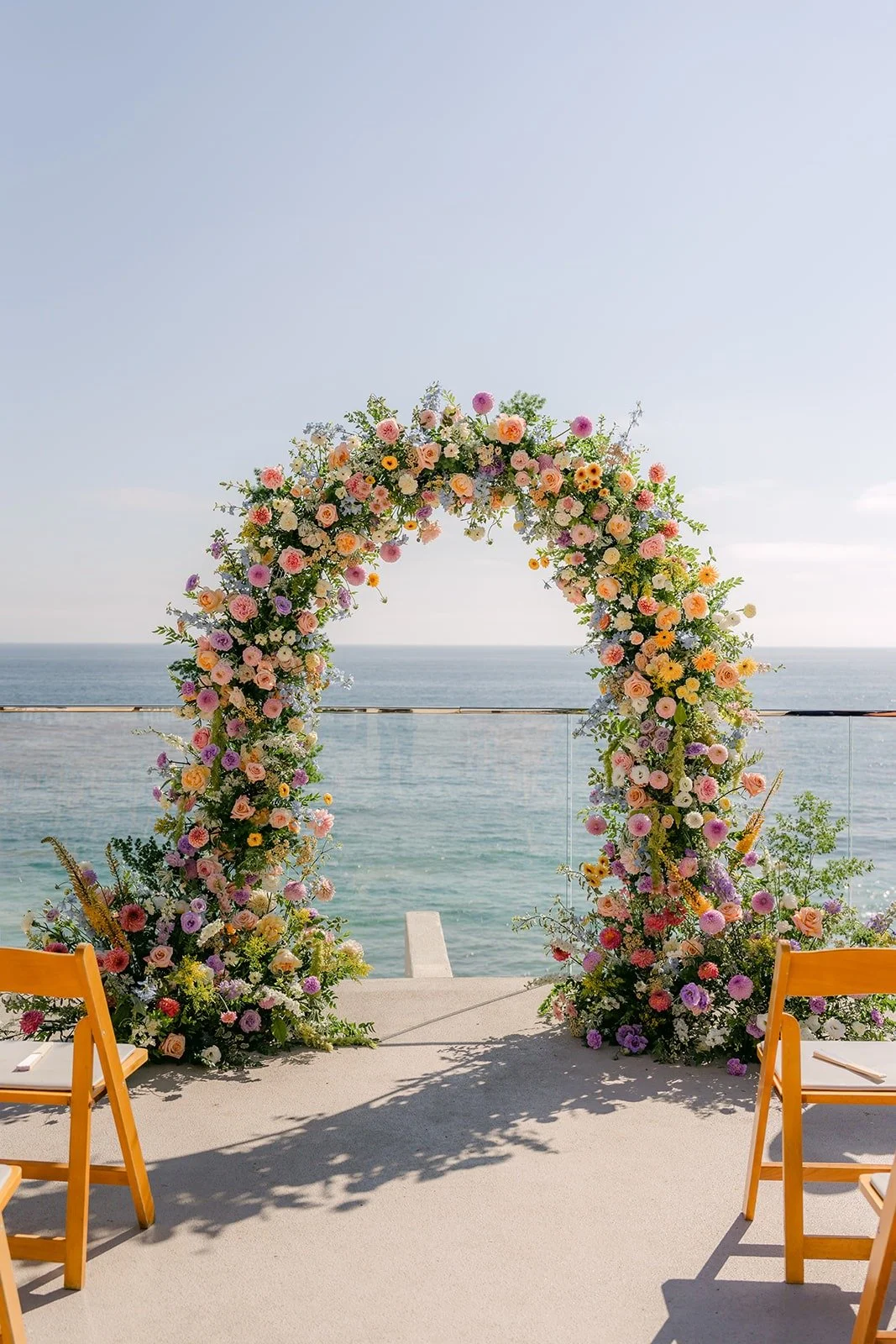 The round floral arch framing the Pacific at the end of the aisle