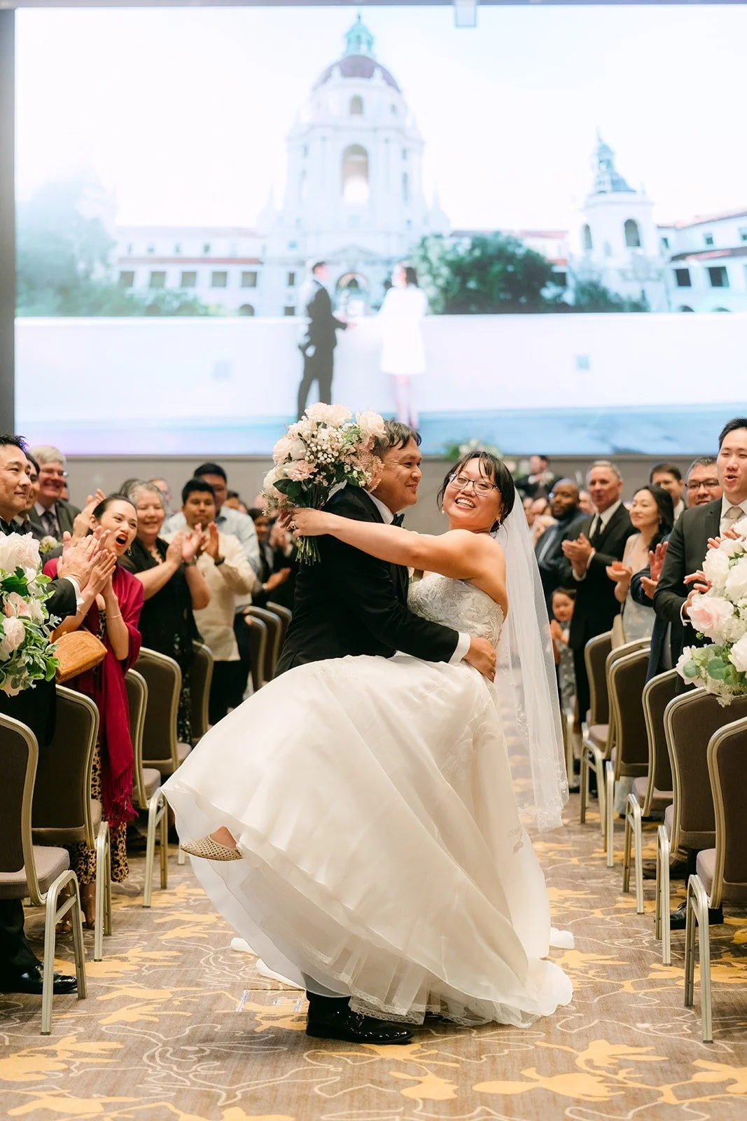 James dipping Stella for a kiss in the aisle as guests cheer, photographed by One and Only Production