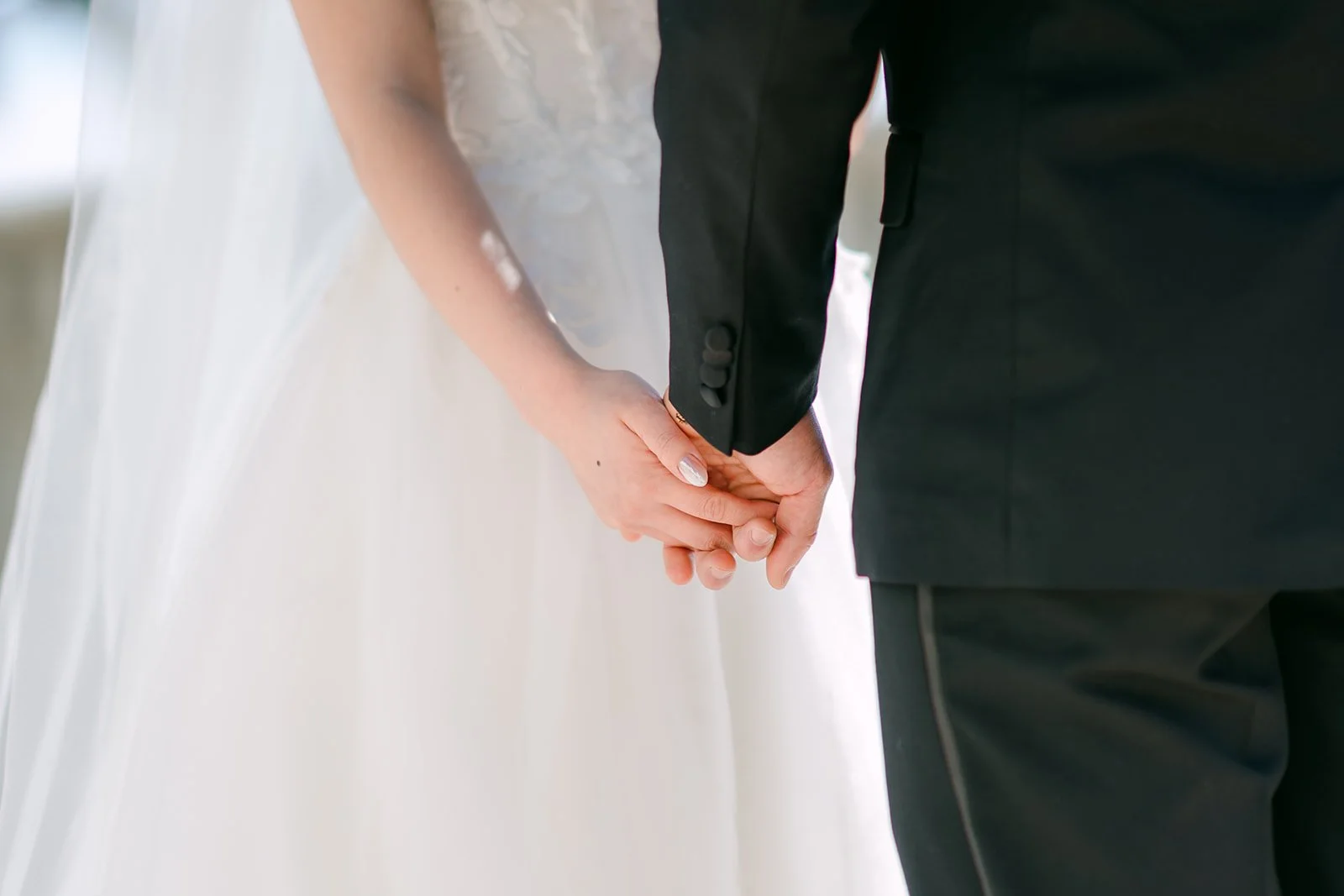 Close-up of the couple holding hands, gown and tuxedo