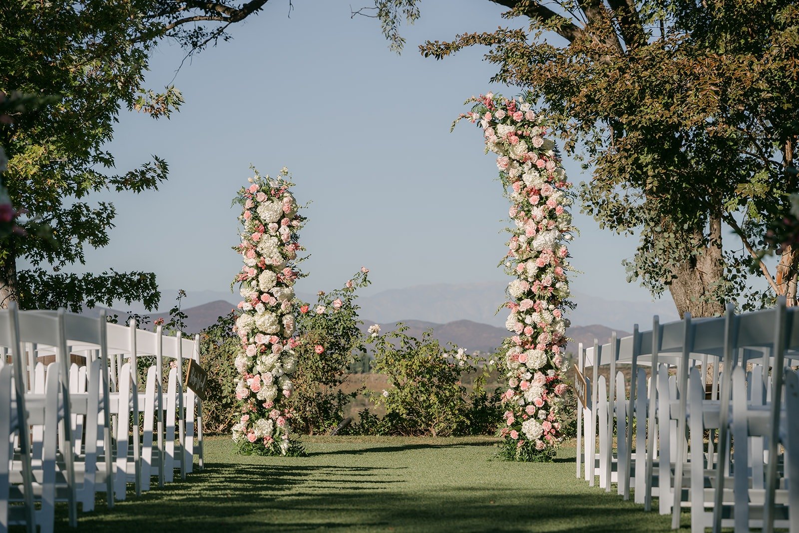 Floral columns and white chairs on the ceremony lawn