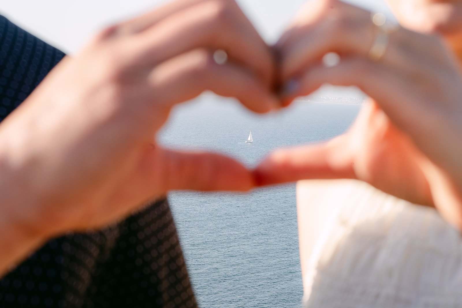 Victoria and Andrew make a heart with their hands against the sky.