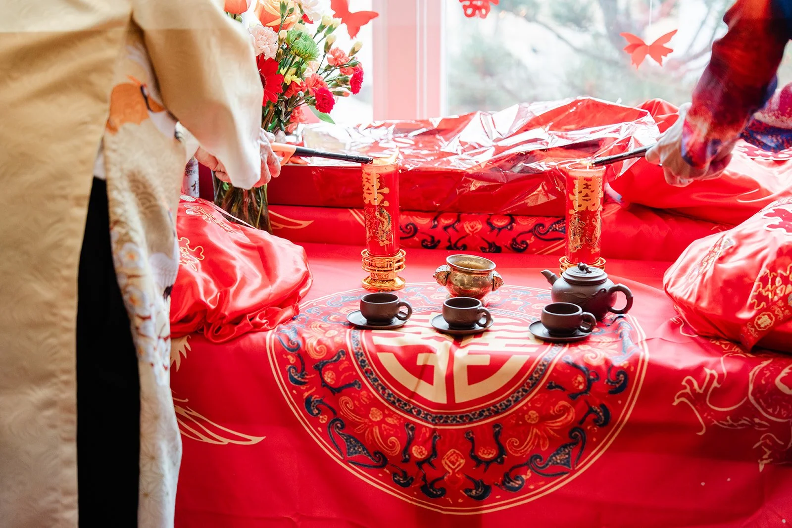 Teacups resting on red embroidered fabric during the tea ceremony.