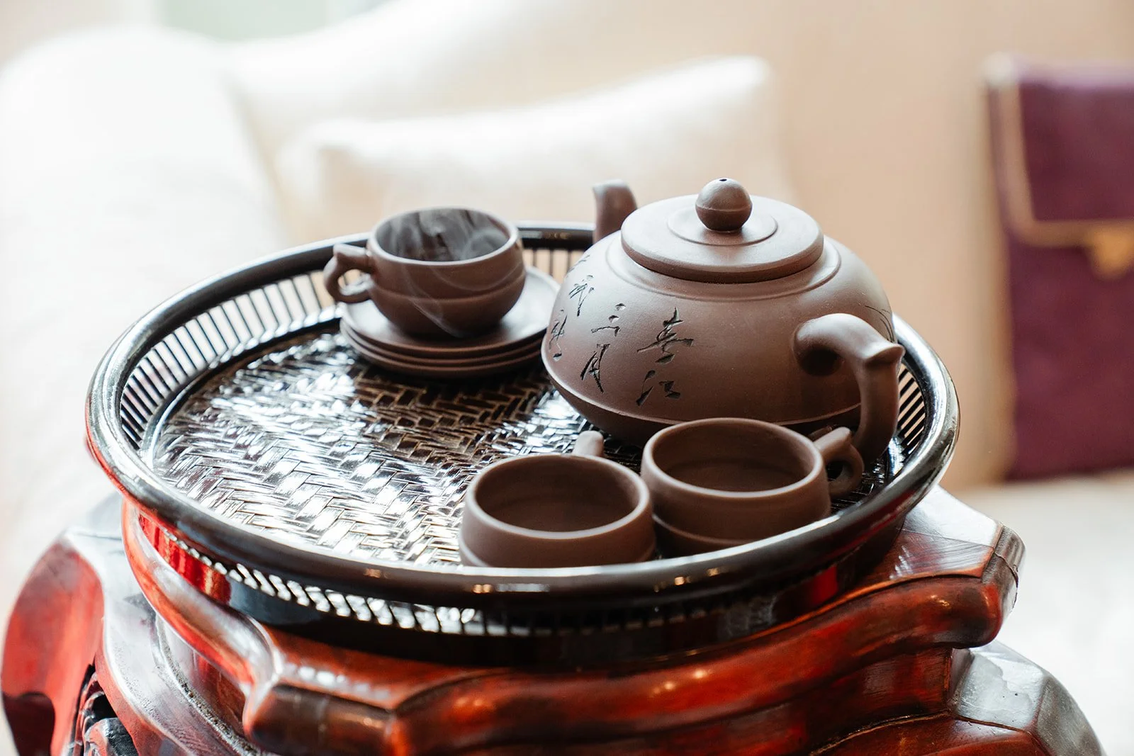 A traditional clay teapot and cups set out on a carved wooden tray.