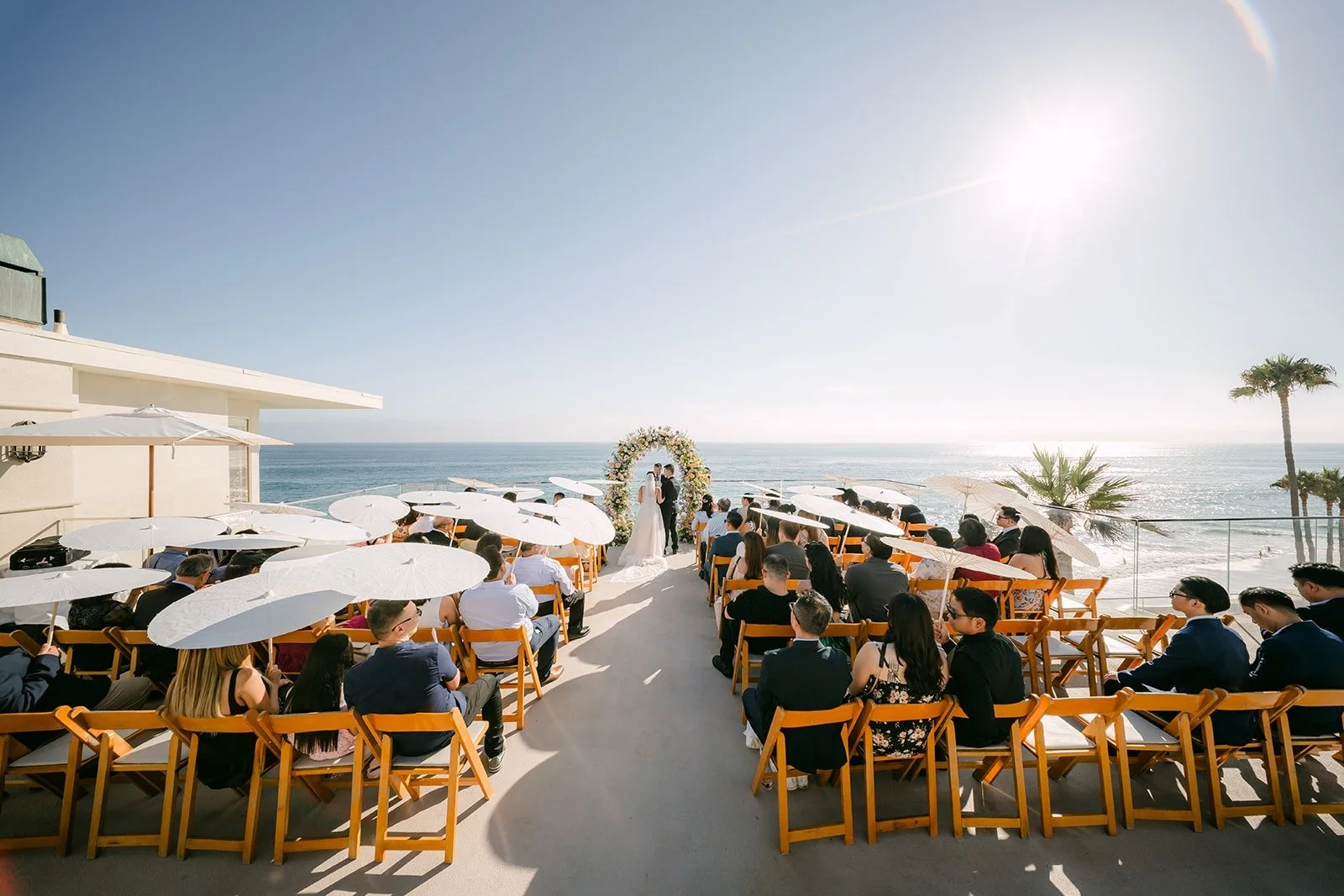 A wide view of the ceremony on the terrace with the ocean and palm trees beyond