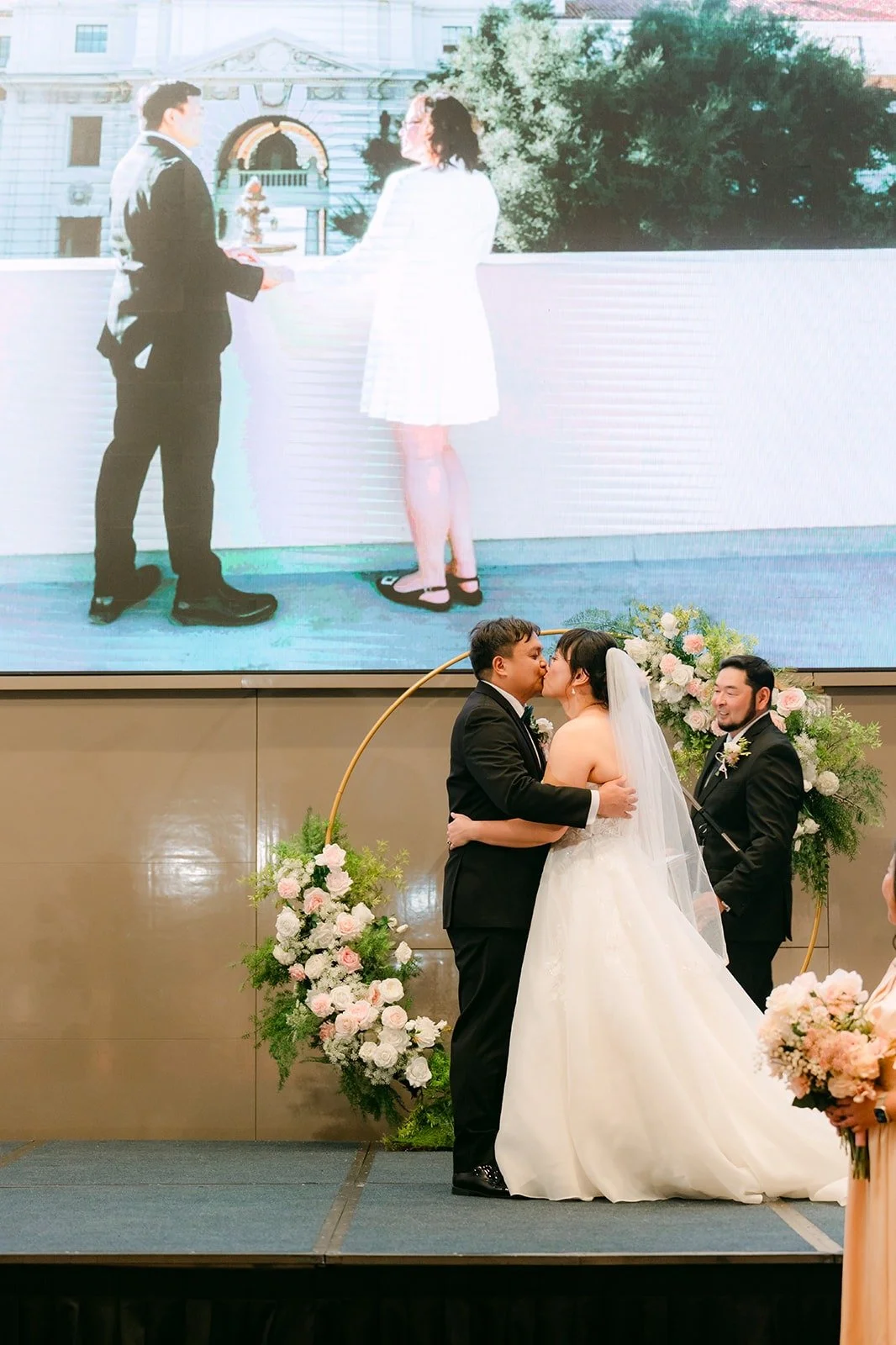 Stella and James sharing their first kiss in front of the floral arch