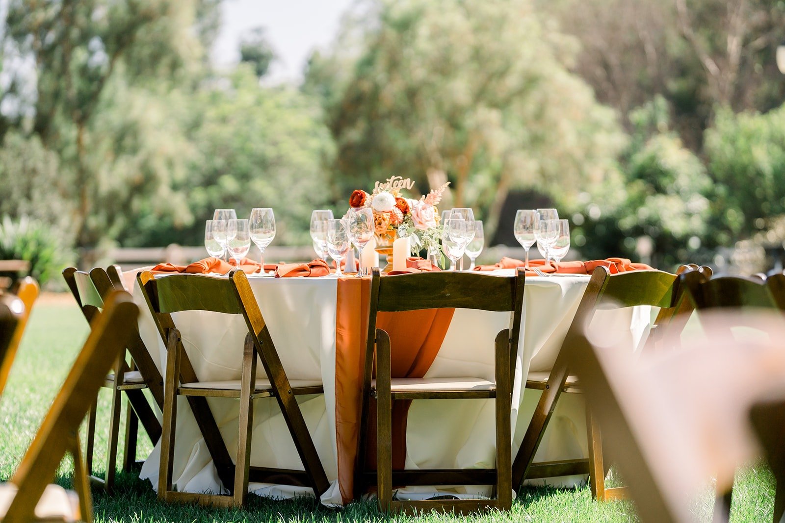 Long reception tables with wooden chairs on the lawn