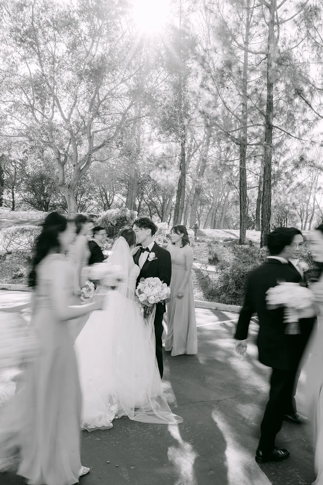 Black and white of the wedding party walking with the couple