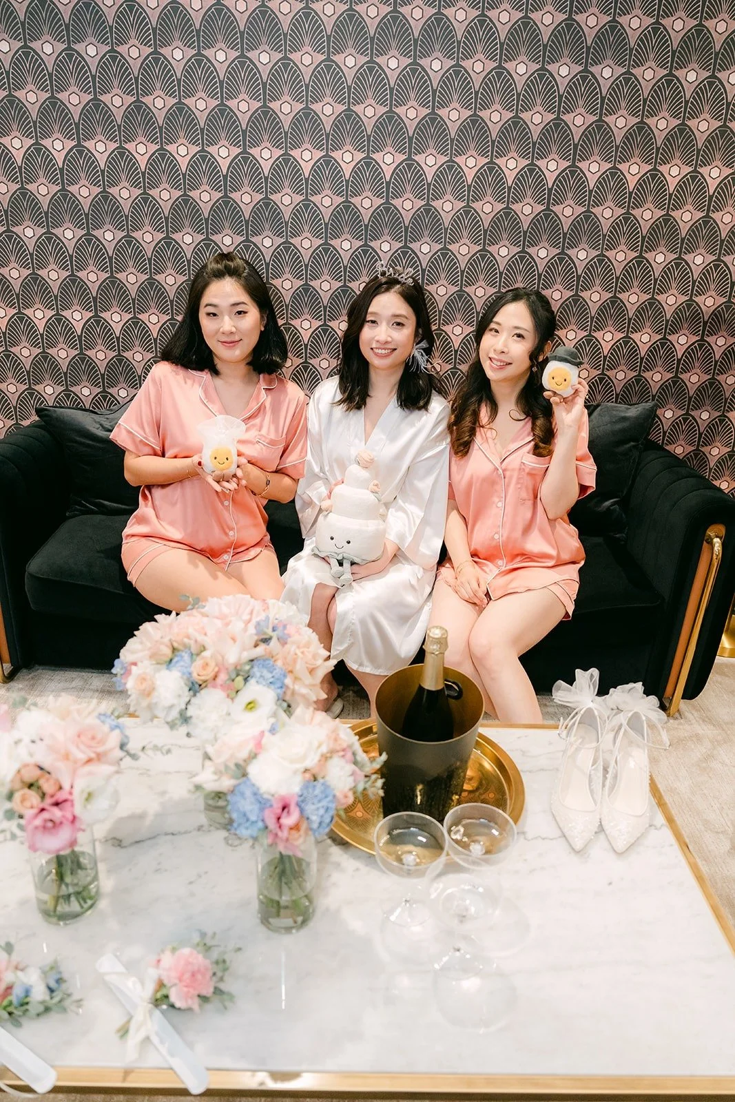 Elisa and her bridesmaids in matching robes on a black sofa in the bridal suite