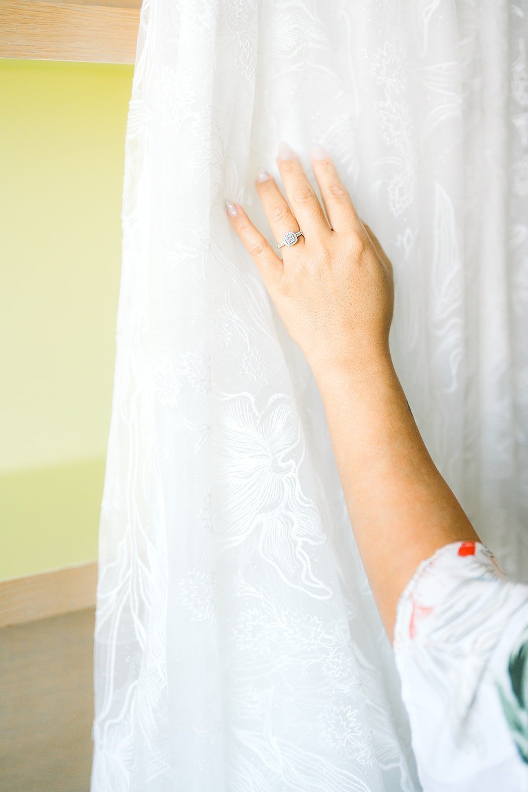 Betsy's hand and engagement ring against the lace of her gown