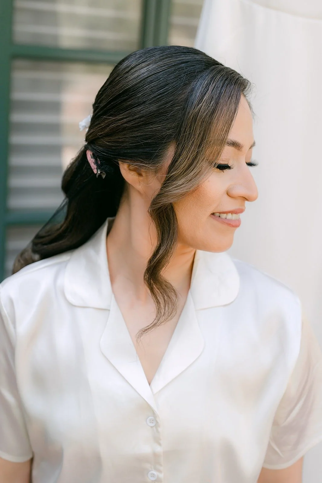 Mariana in her robe smiling over her shoulder with her hair styled in soft waves