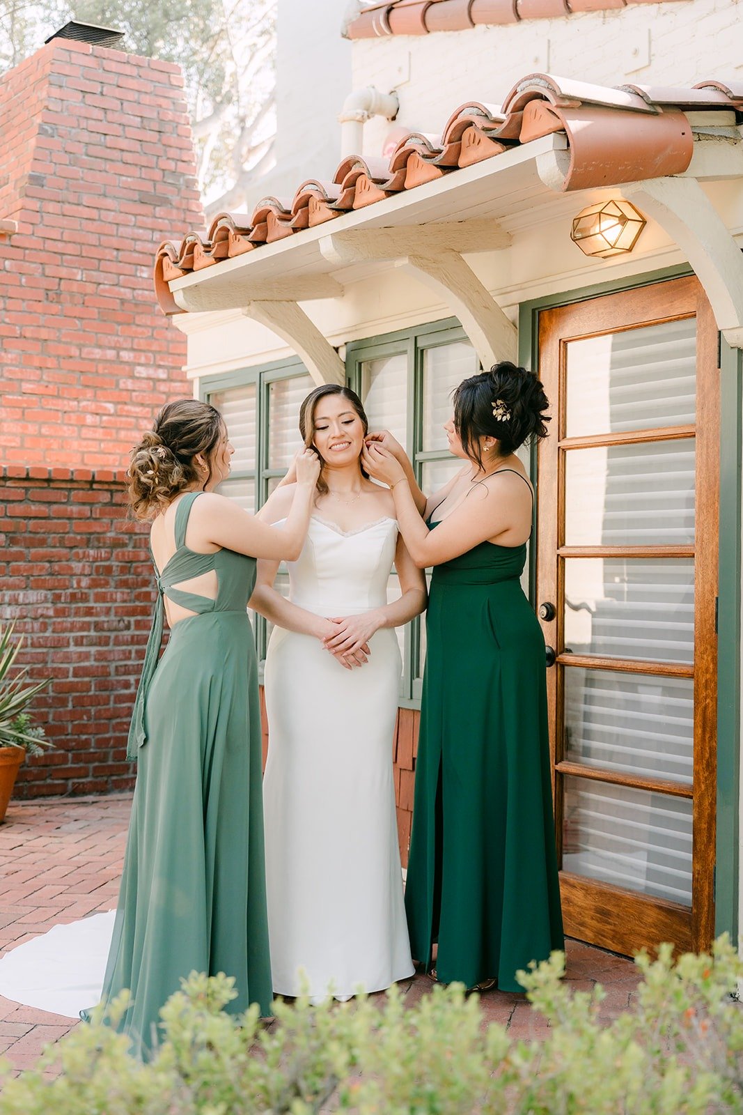 Mariana with two bridesmaids in green outside the bridal cottage