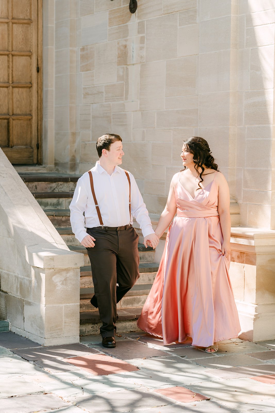 Saira and Matthew walking down the stone steps from the mansion's carved doorway.