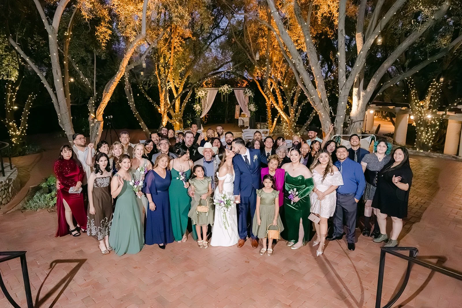 Group photo with all of their guests in the courtyard under string lights