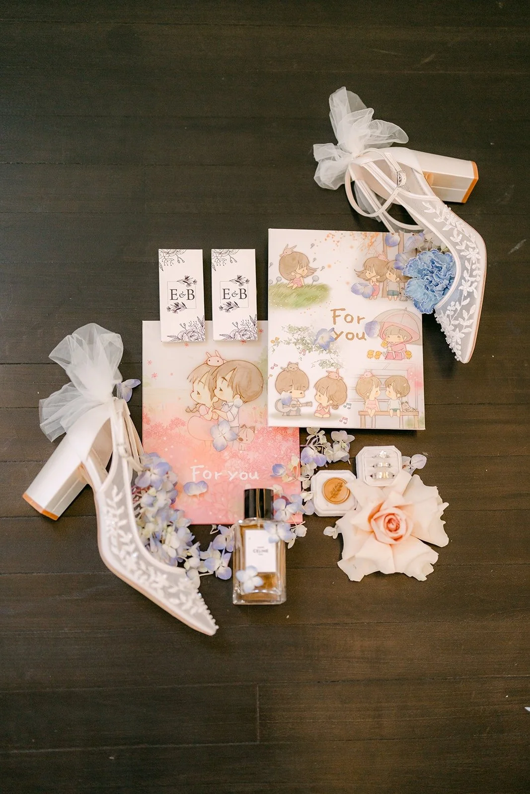 Elisa's lace heels, perfume, stationery and blue and blush flowers laid out as a flat lay