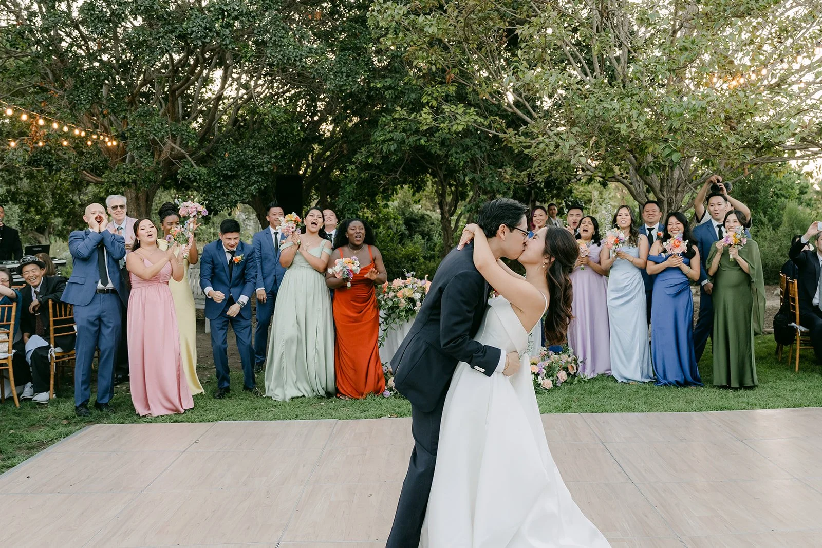 A dip kiss on the dance floor as the wedding party cheers