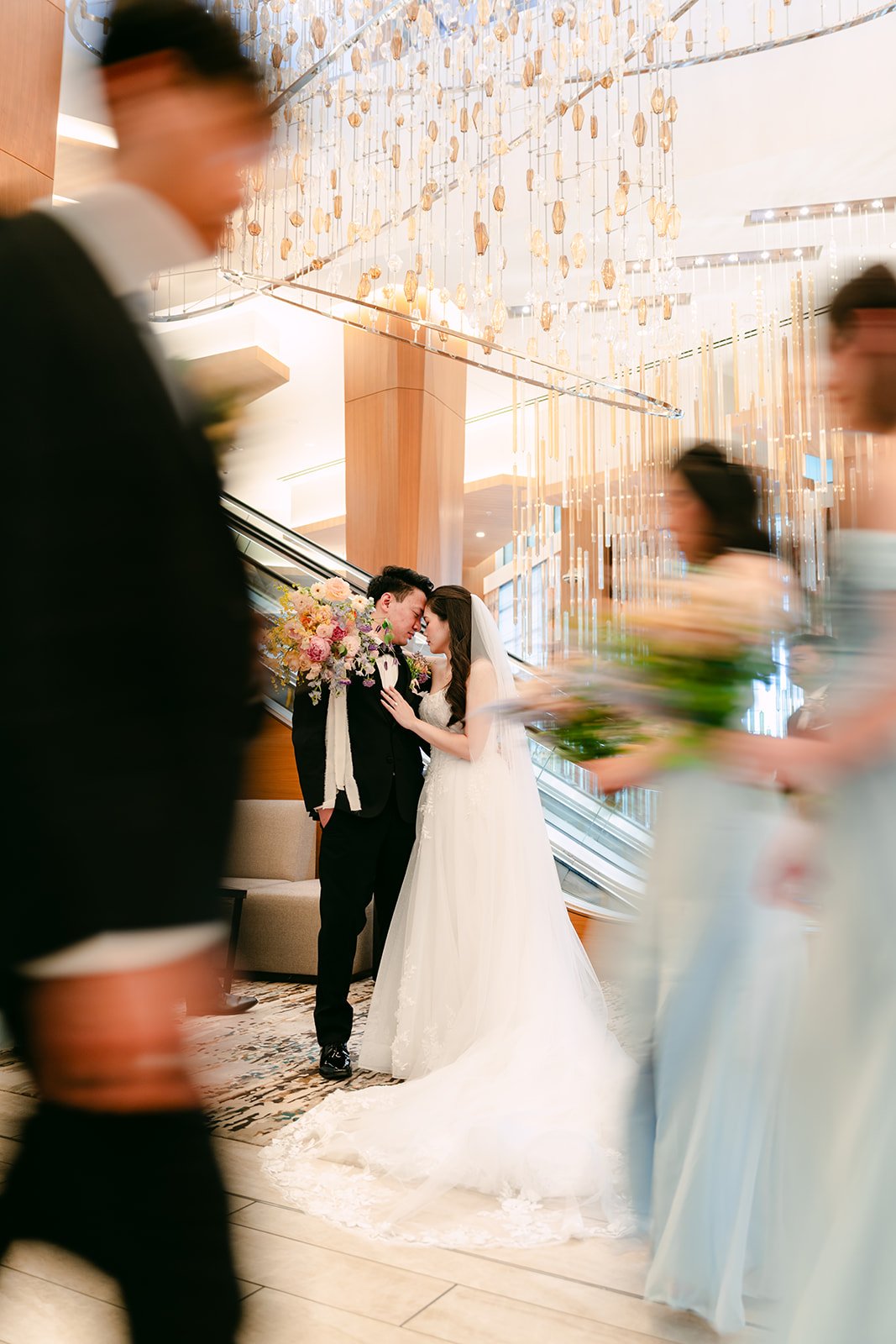 Linh and Hoan kissing as the wedding party moves past in motion blur