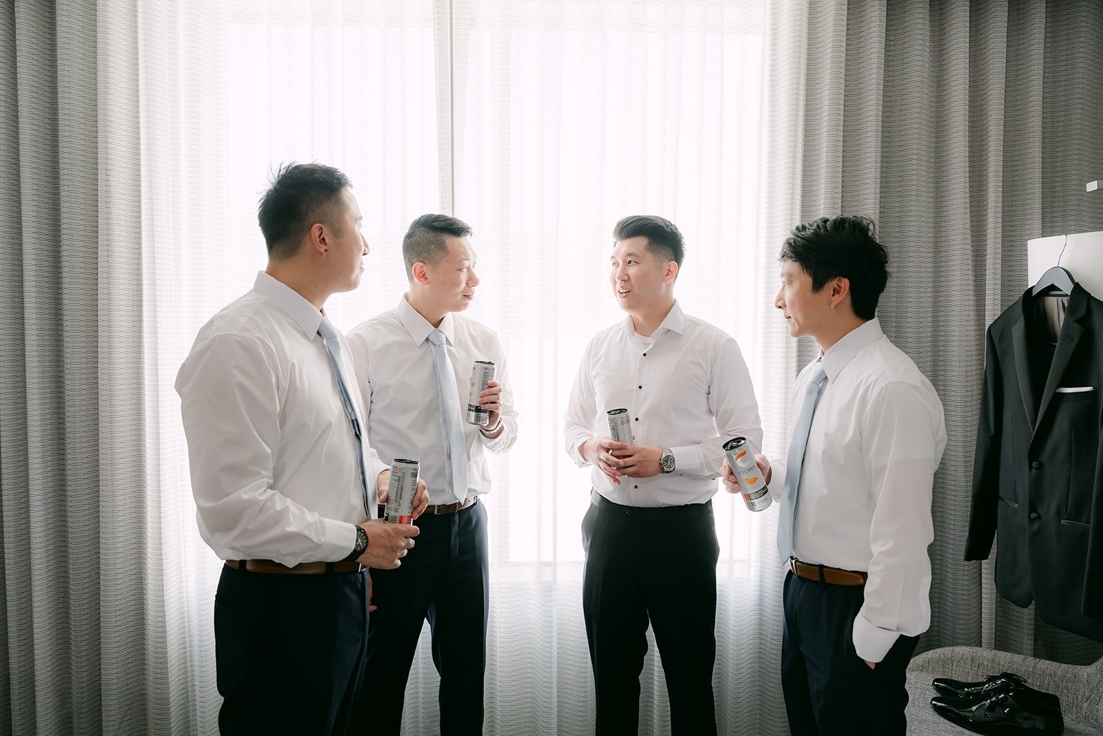 San and his groomsmen getting dressed in white shirts.
