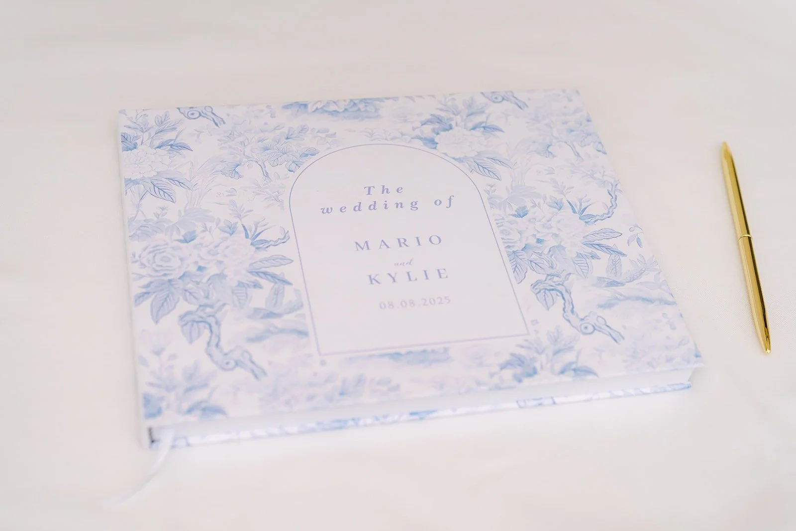 The guest book with a blue floral cover and a gold pen