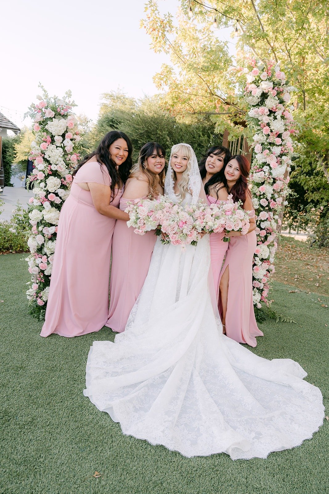Bridesmaids laughing around Konitha by the ceremony arch