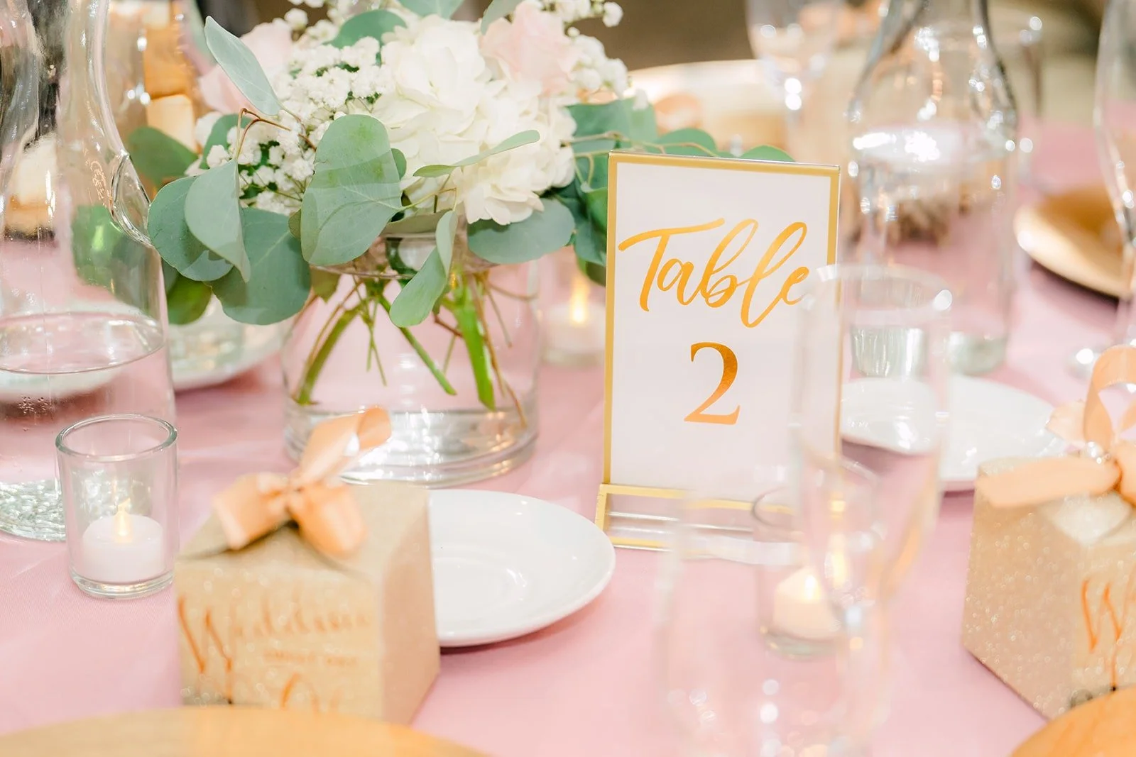 Table number and blush florals on a reception table