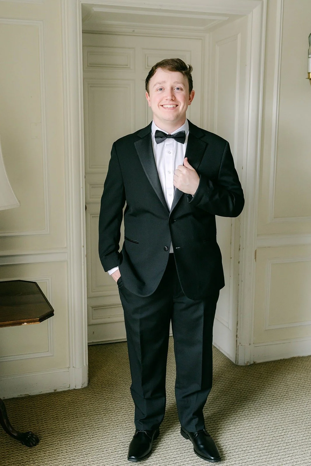 Matthew smiling in his tuxedo in a bright room at The Athenaeum