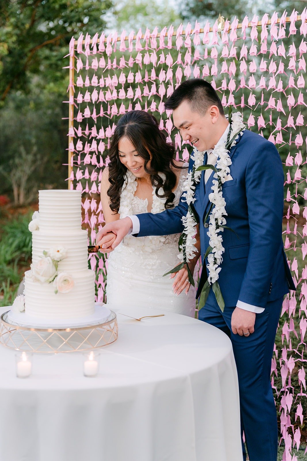 Kelli and Alex at the cake table in front of the pink paper crane wall