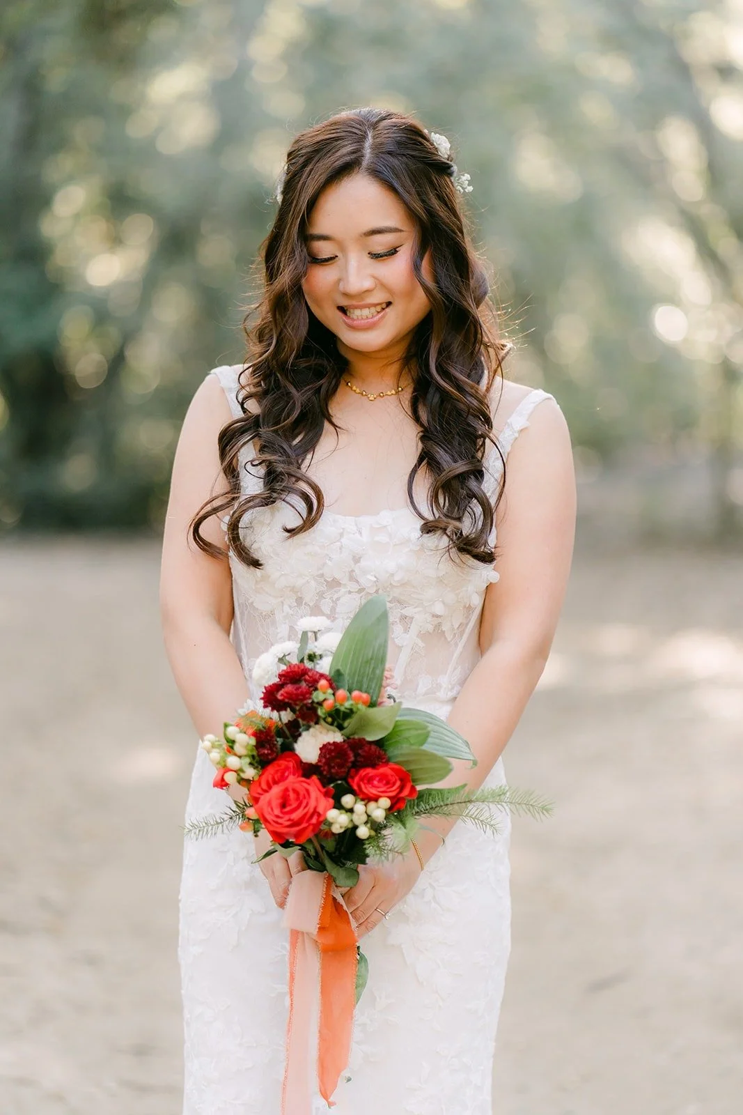 Shayna smiles down at her red and orange rose bouquet