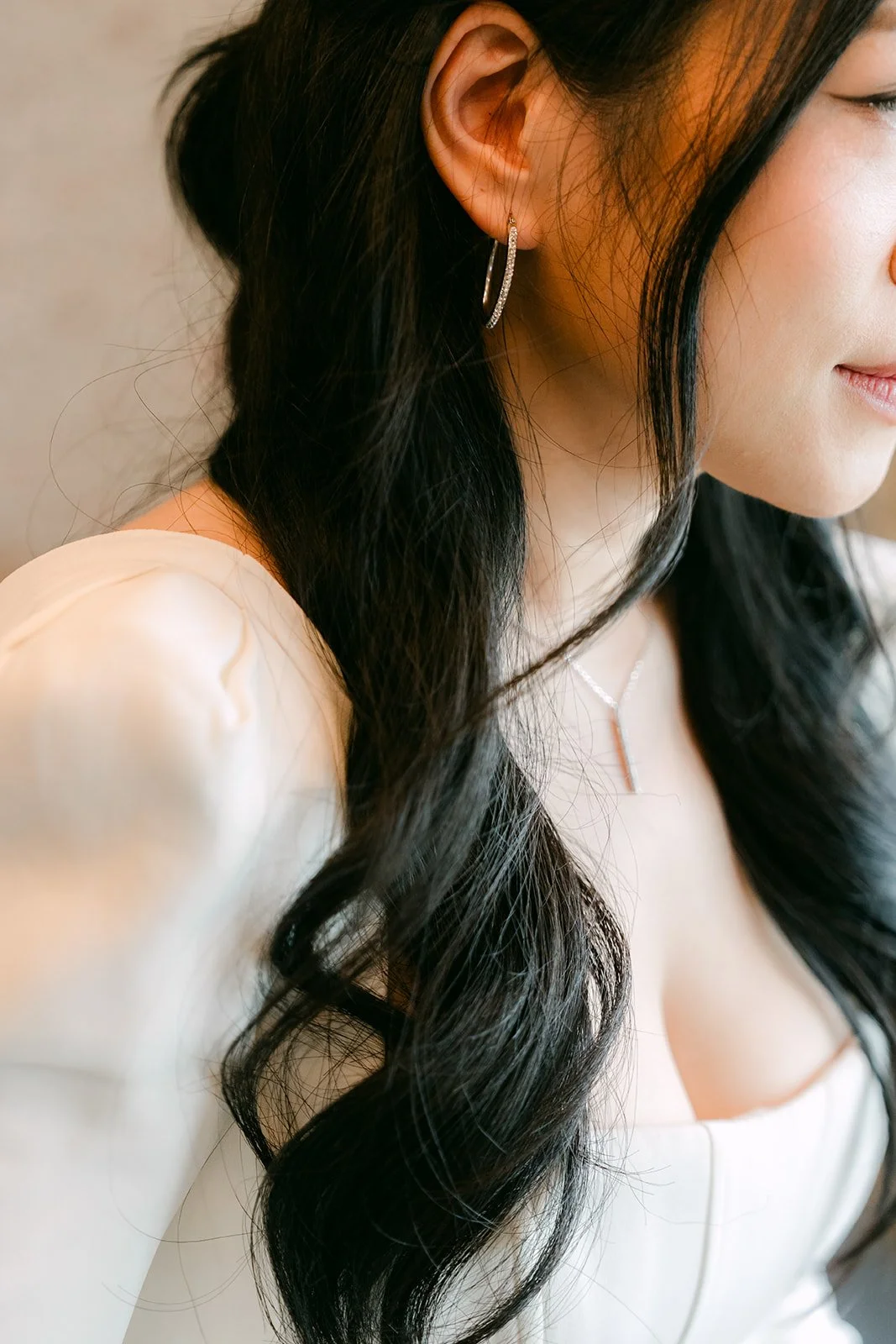 Profile detail of Denise's earring and long dark waves.
