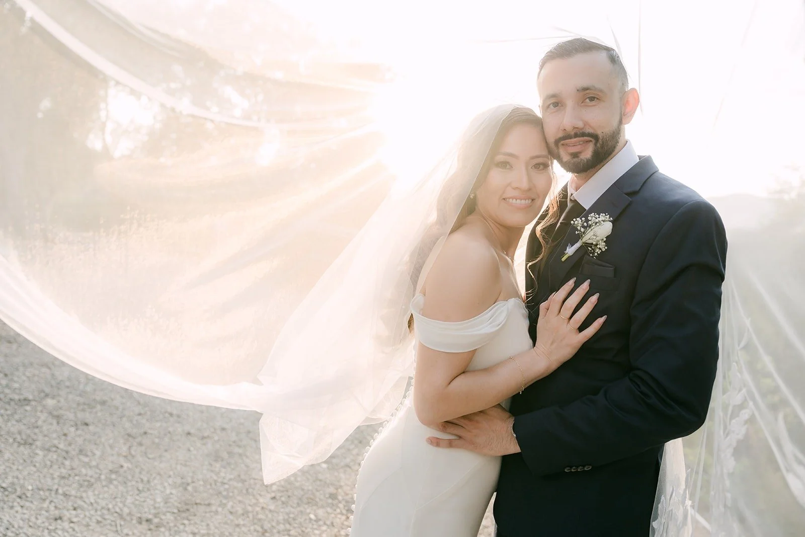 Mariana and Danny smiling as her veil catches the wind