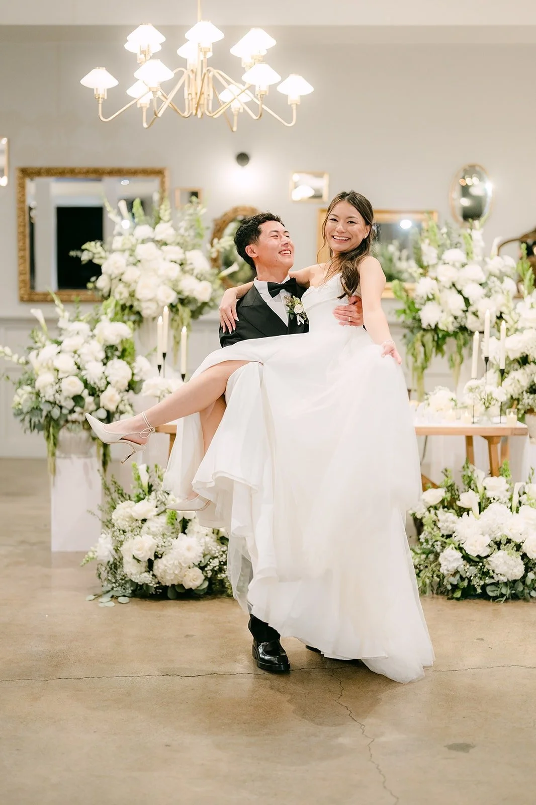 Richard lifting Jadee in front of the white floral backdrop