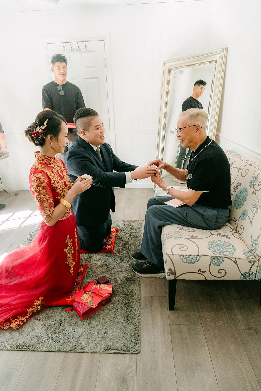 A bride and groom kneeling to serve tea to the groom's parents.