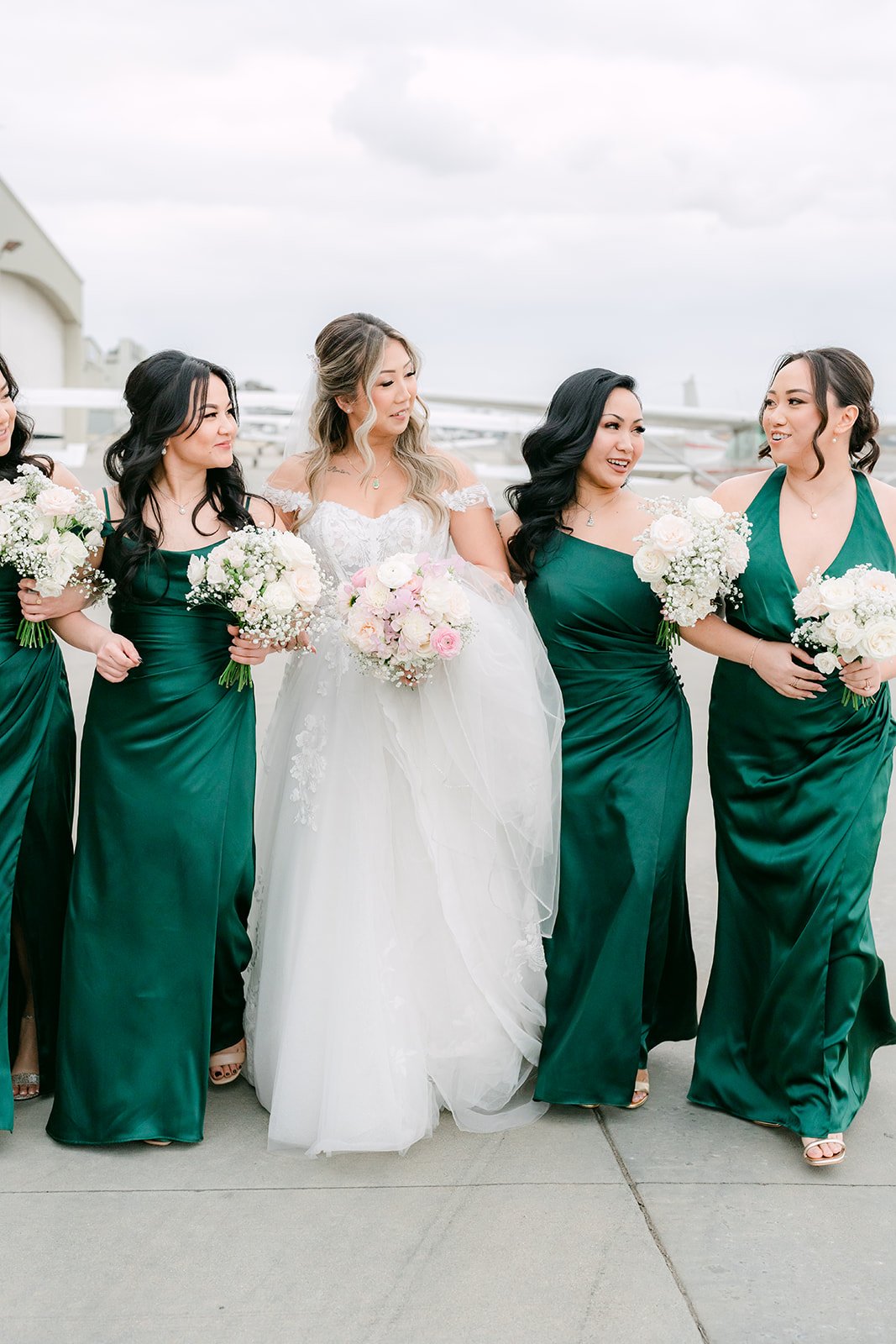 Bride laughing with her bridesmaids on the tarmac
