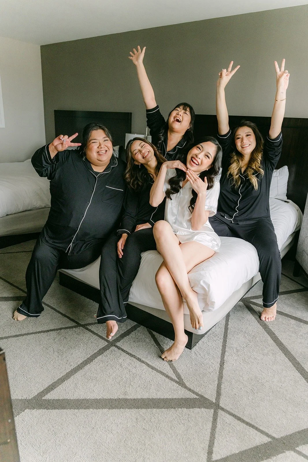 Natalie and her bridesmaids in matching pajamas cheering on a sofa at the DoubleTree by Hilton Norwalk