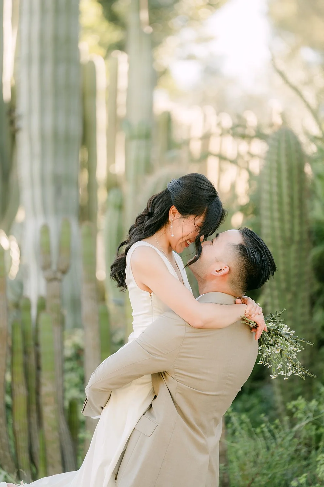 Kim laughing as Vincent lifts her among the tall cacti.