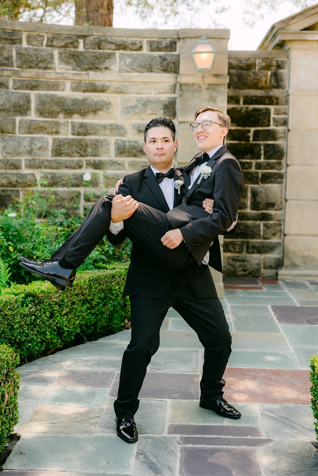 A groomsman lifting Nik in the Greystone courtyard