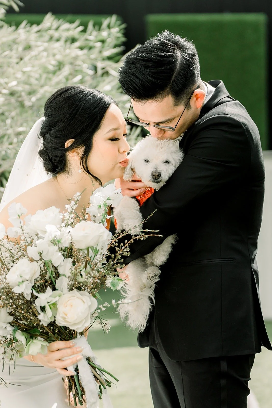 Alex holds the white dog as Cindy leans in