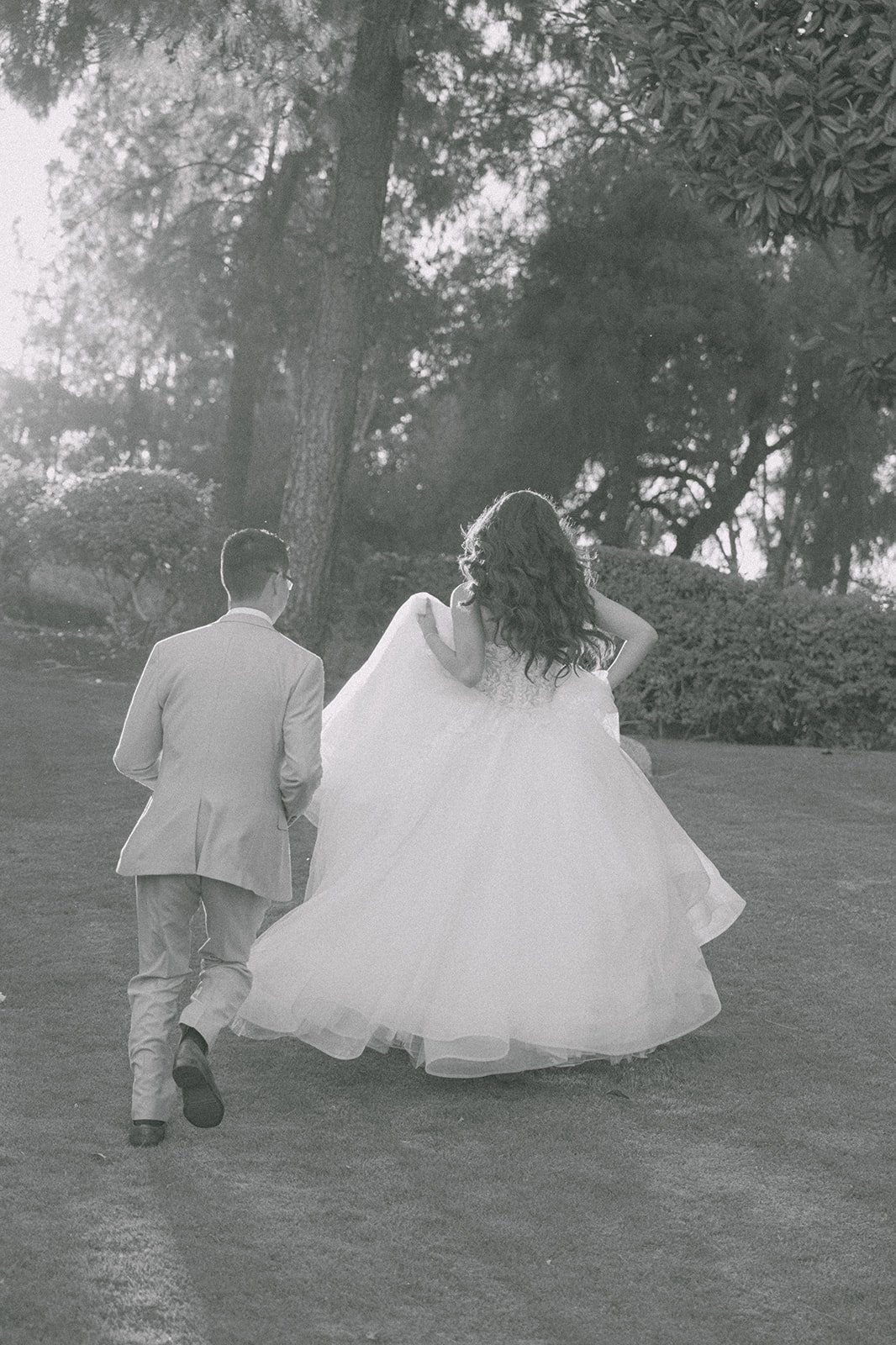 Black and white photo of Kevin leading Sandra across the lawn at sunset.