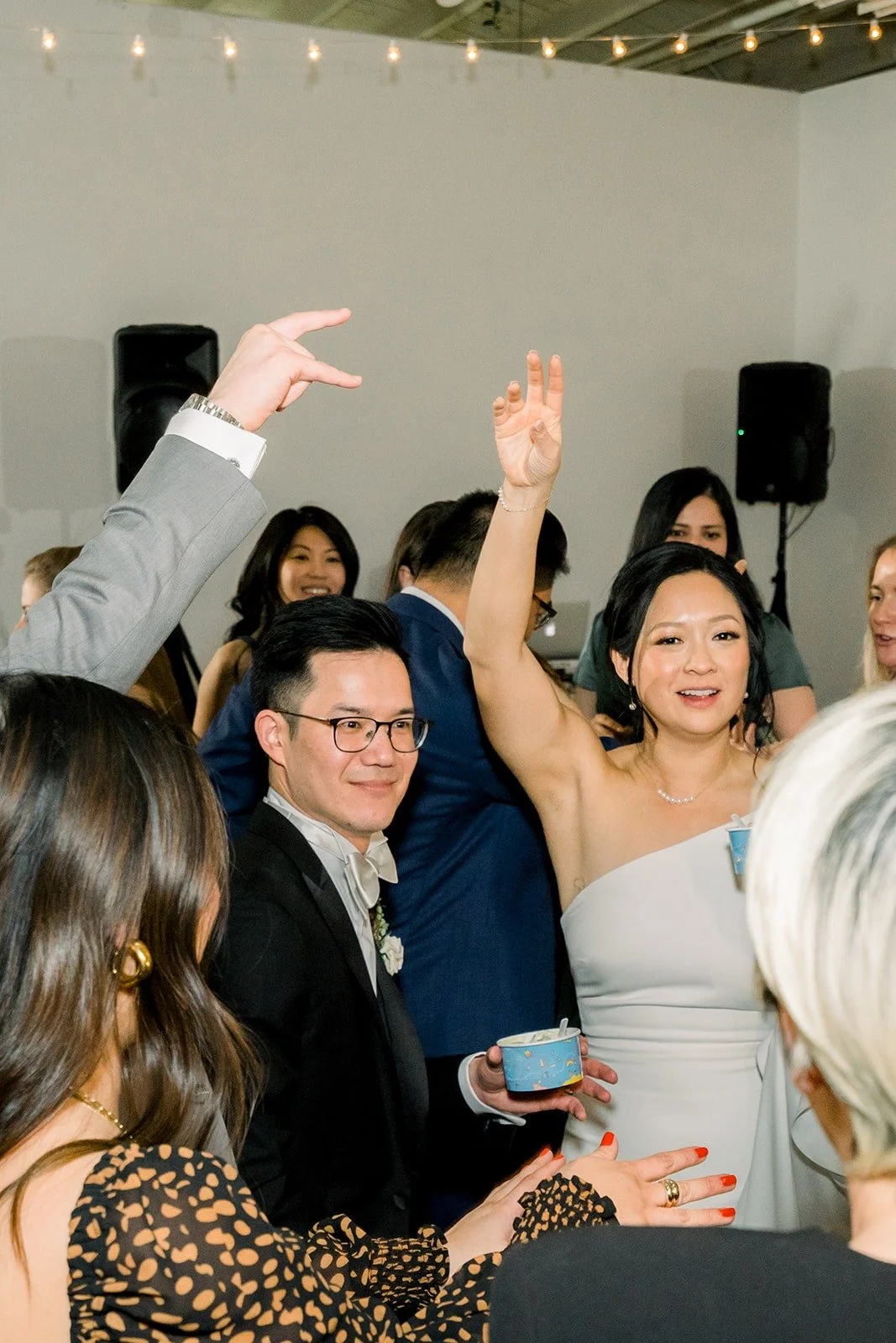Cindy throws her hands up as friends cheer around her