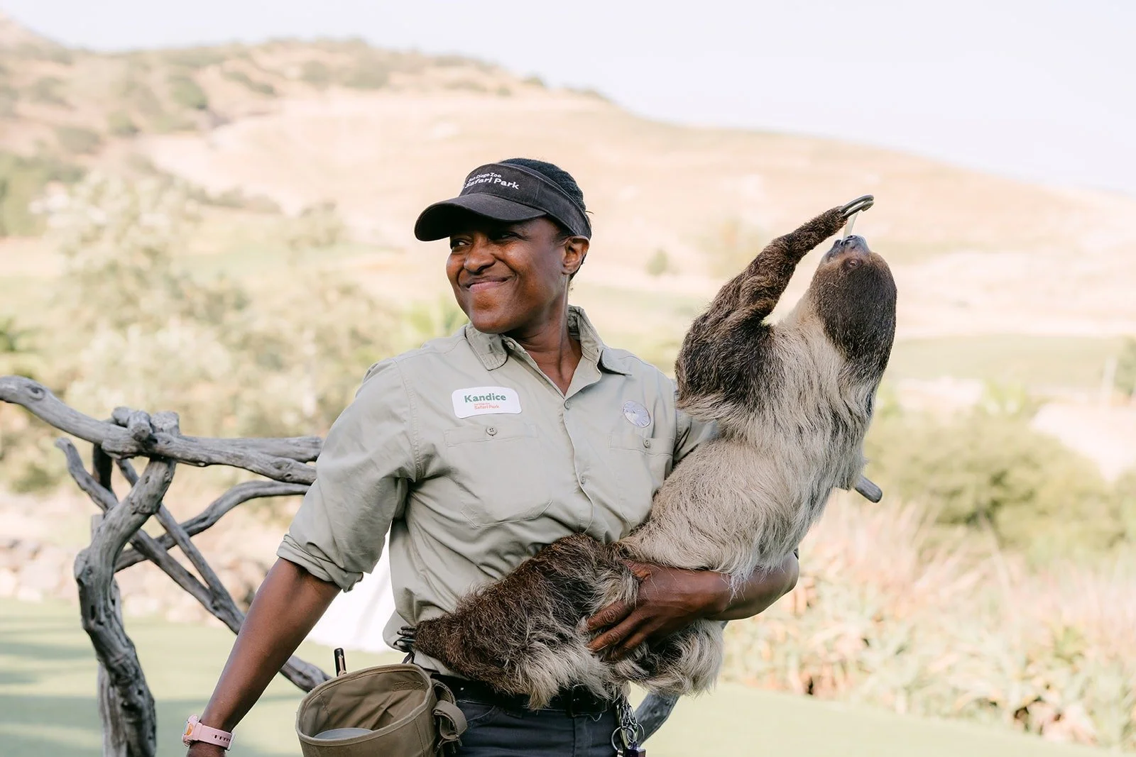 An animal care specialist smiling with a sloth in her arms