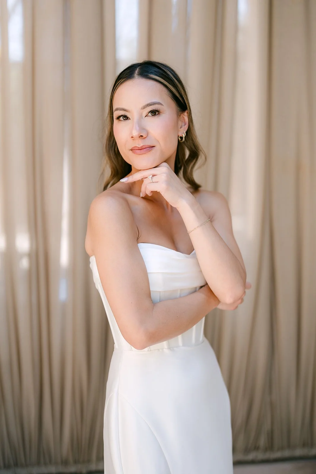 Portrait of Kieu in her strapless gown against the warm drapery