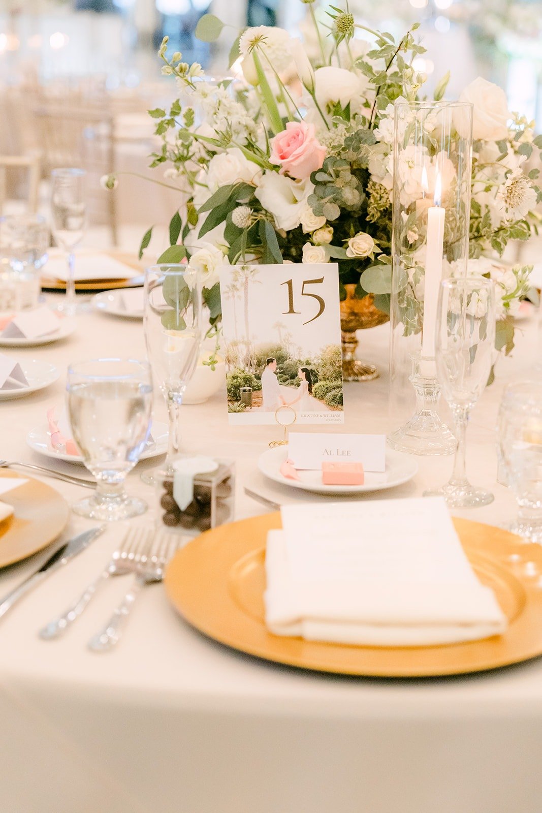 A place setting with a gold charger and menu under blush flowers