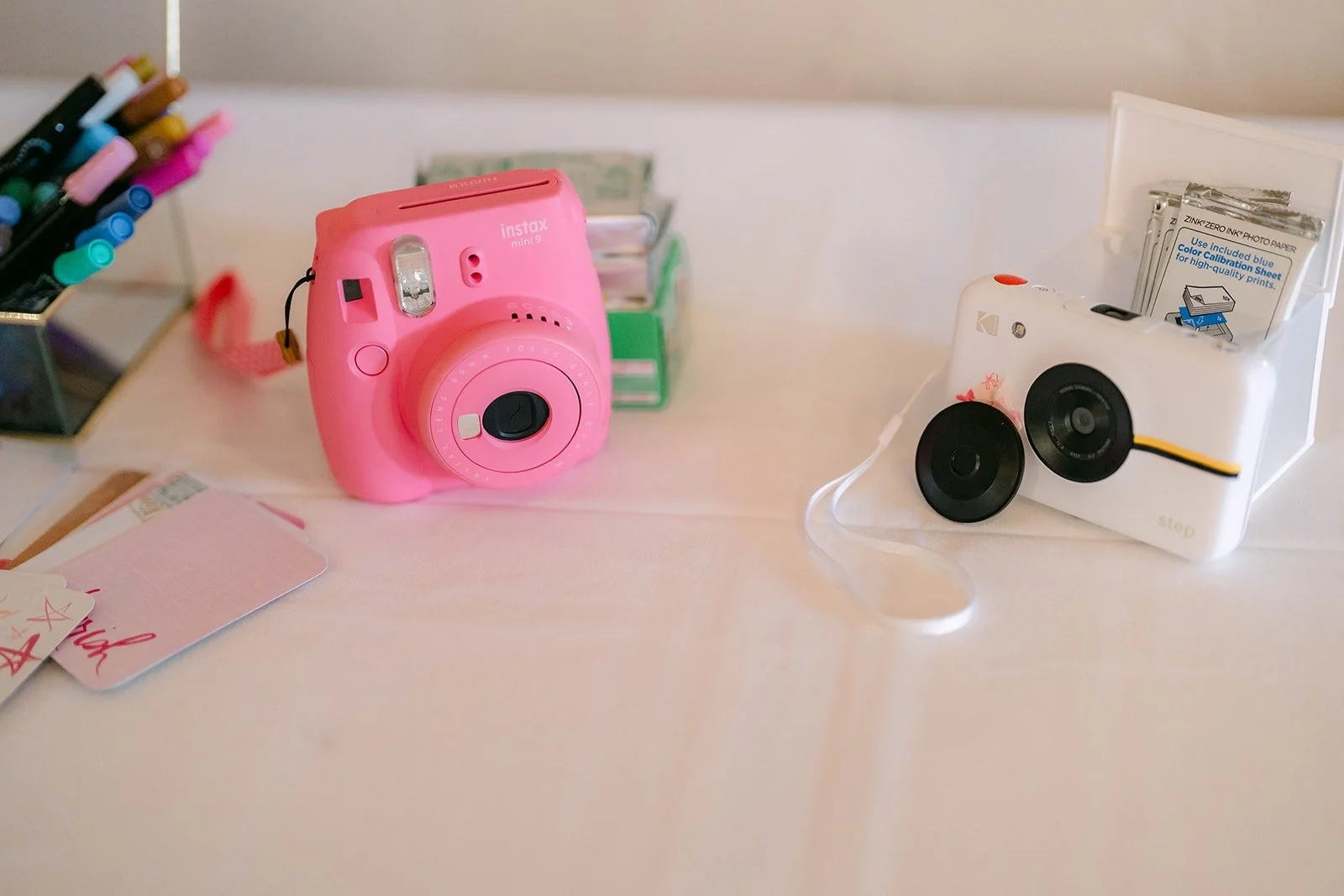 A pink instant camera and a photo guest book on a white table