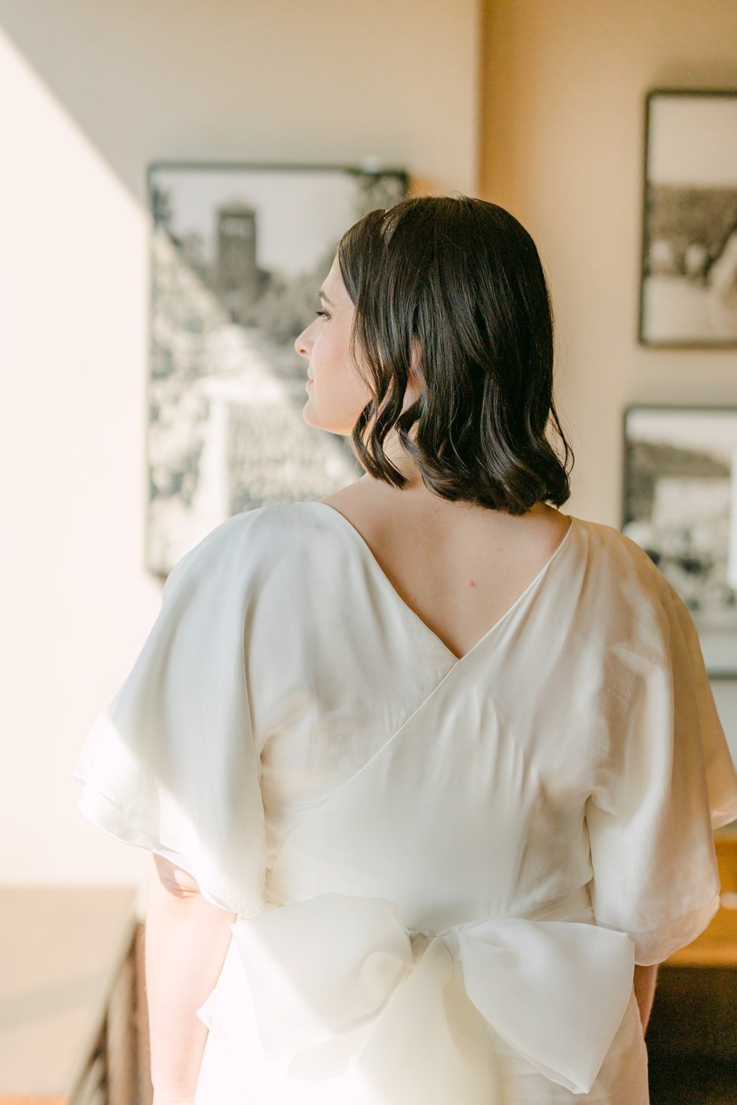 Jessie from behind, showing the flutter sleeves and bow of her dress