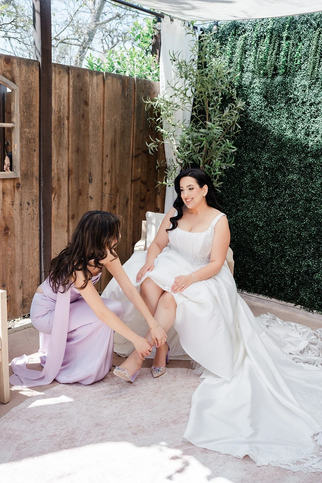 Bridesmaid helping the bride with her shoes
