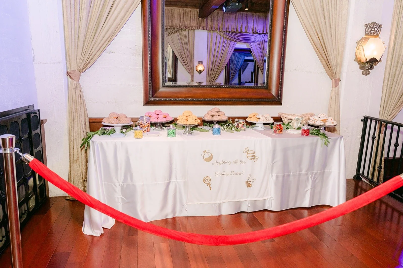 The sweetheart table with florals beneath a gold framed mirror