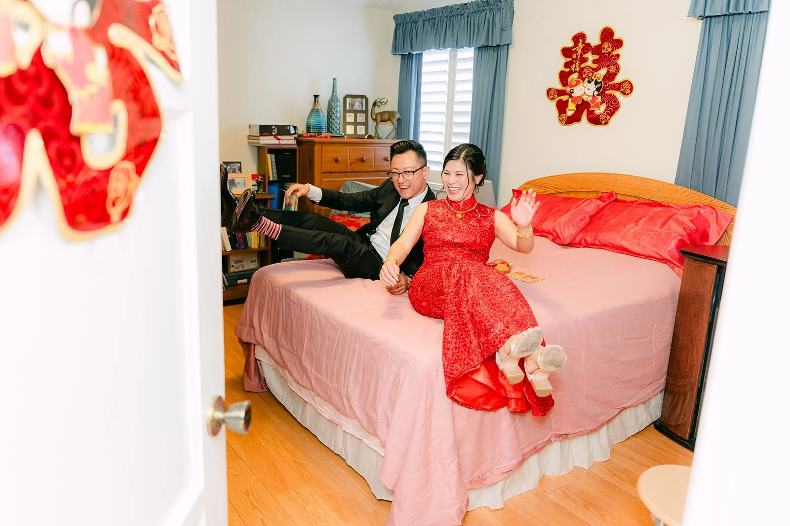 Xuemin resting on a bed with red double happiness decor, photographed by One and Only Production