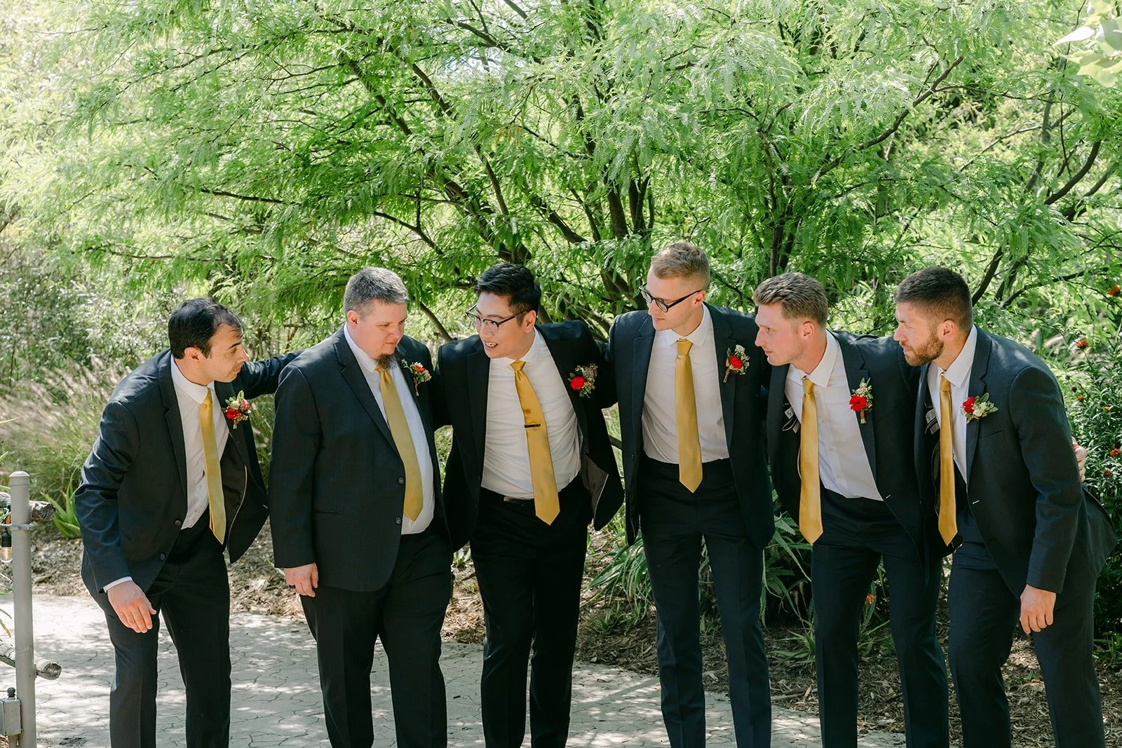 The groomsmen laughing together in their suits and gold ties, photographed by One and Only Production