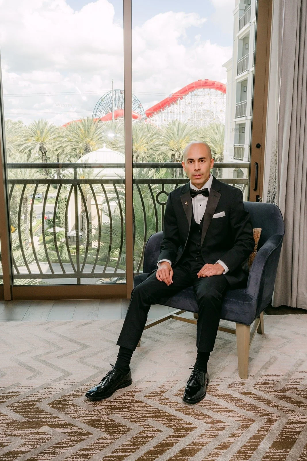 Daniel seated by the balcony window in his black tuxedo